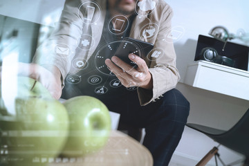 hipster using smart phone for mobile payments online business,sitting on sofa in living room  and holding green apple in wooden tray,virtual computer interface omni channel