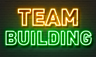 Team building neon sign on brick wall background.