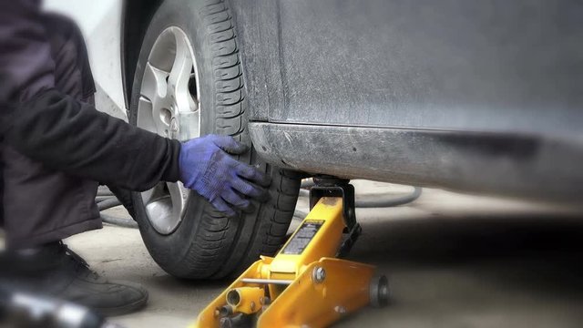 Car mechanic screwing car wheel 