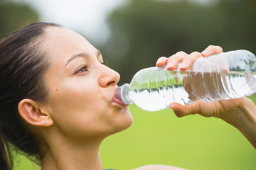 Young exercising woman drinking water