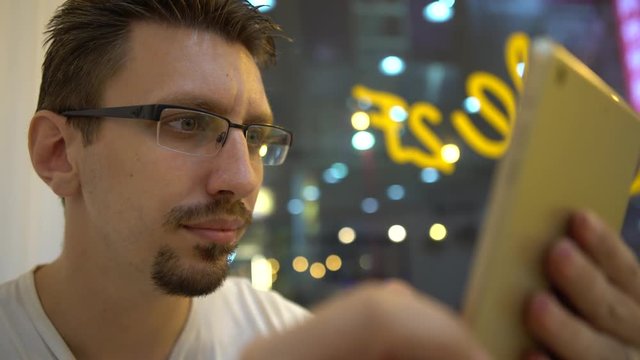 4K Caucasian Young Man using tablet touch screen to chat and contact people on the distance in a coffeeshop. European Man in a cafe shop Surfing the internet with modern wireless technology-Dan