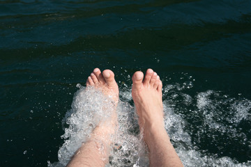 Fototapeta na wymiar Dipping feet in water off a dock on a hot summer day.