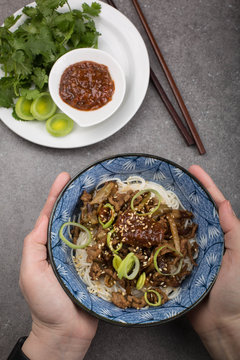 Dan Dan mian- a traditional noodle dish from Sichuan Province in China. Hands are holding a bowl
