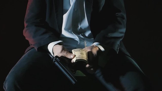 close-up hands of a dangerous man with a gun counts the money. Dirty Money Mafia.