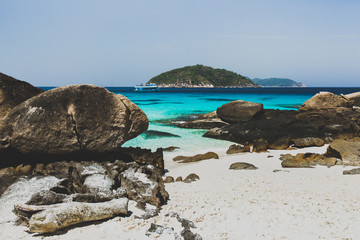 White sand beach with large black stones. Tropical island
