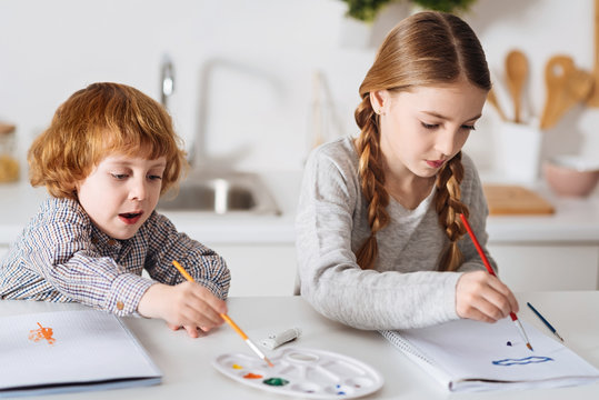 Determined creative siblings painting in the kitchen