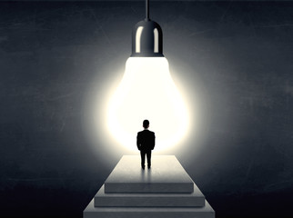 Man standing on a step in front of a huge light bulb
