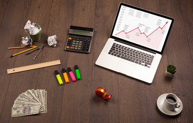 Computer desk with laptop and red arrow chart in screen