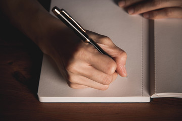 Close up of  people hand  writing on notebook on wooden table