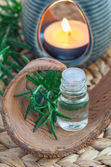 Rosemary essential oil in glass on woven mat with spa background, vertical