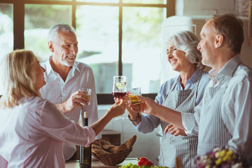 Positive aged couples celebrating in the kitchen