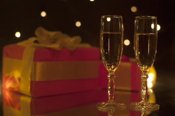 Romantic composition two goblet of champagne and gifts in blurring