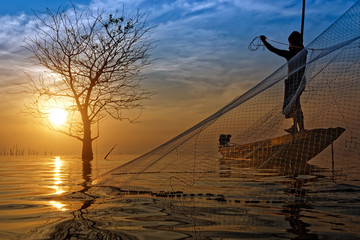 Silhouettes fisherman throwing fishing nets during sunset, Thailand.