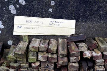Pile of old used recycled house bricks with a for sale sign