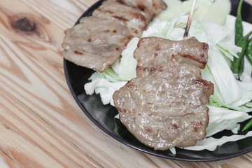 grilled pork meat and vegetables in plate with on wood background
