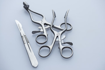 Two retractors and scalpel on a blue background
