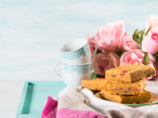 Festive breakfast set pastel color tray. Flowers roses Valentine's Mother day home made baked treat with candies. Peanut butter blonde bownies.