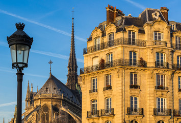 Fototapeta na wymiar Haussmannian building facade on Ile de la Cite with Notre Dame Cathedral Spire and street lamp post. 4th Arrondissement, Paris, France