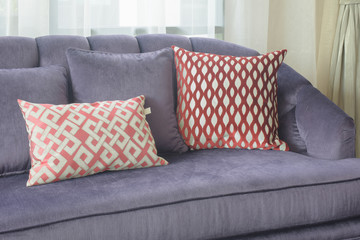 Red pattern pillows lay on viloet sofa in living room