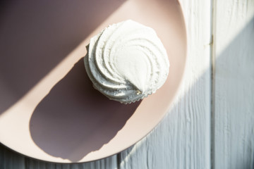 White sweet marshmallow air and gentle pink round dish on a white wooden table