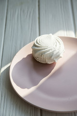White sweet marshmallow air and gentle pink round dish on a white wooden table