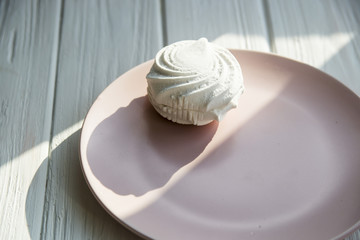 White sweet marshmallow air and gentle pink round dish on a white wooden table