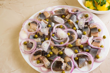 Sliced herring on a white plate and boiled potatoes