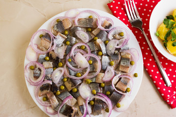 Sliced herring on a white plate and boiled potatoes