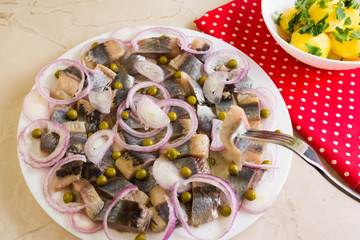 Sliced herring on a white plate and boiled potatoes