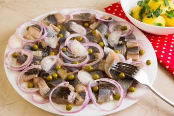 Sliced herring on a white plate and boiled potatoes
