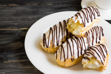 Eclairs in white glaze on a white plate. Delicious dessert.