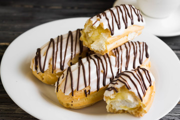 Eclairs in white glaze on a white plate. Delicious dessert.