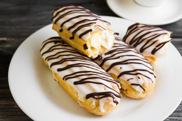 Eclairs in white glaze on a white plate. Delicious dessert.