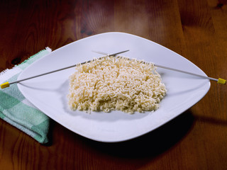 Closeup of a plate, with Chinese pasta, as if it had been made with knitting needles.
