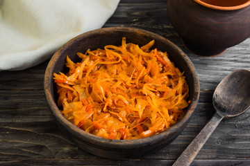 Braised cabbage in a wooden bowl on a wooden table in rustic style