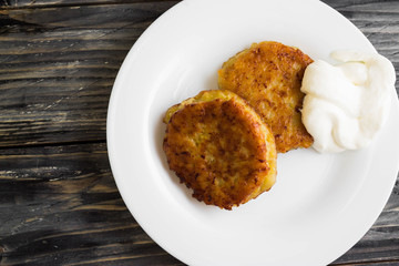 Potato patties with sour cream on a wooden table in rustic style