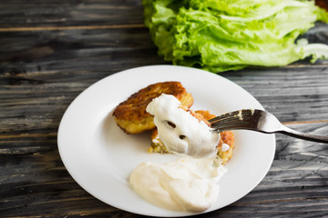Potato patties with sour cream on a wooden table in rustic style