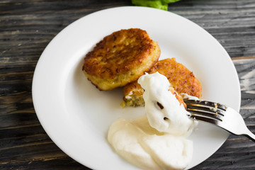 Potato patties with sour cream on a wooden table in rustic style