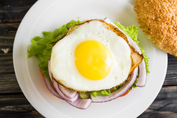 Hamburger with fried eggs and beetroot on a wooden table and ingredients