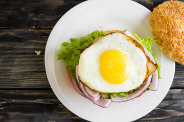 Hamburger with fried eggs and beetroot on a wooden table and ingredients