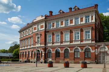 Fototapeta na wymiar Red brick classic building from 19th century. Bright sunny day in European city.