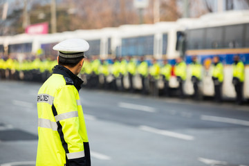 Many policemen in the background, one in foreground