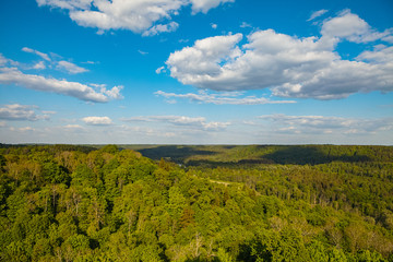 Beautiful sky and clouds over hills with green forest, covered by sunshine. Gauja river, Latvia.