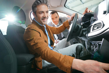 Man sitting inside vehicle in car dealership