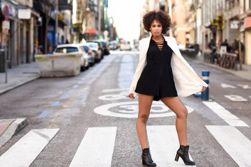 Fototapeta premium Young black woman with afro hairstyle standing in urban background