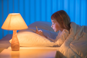 The cute girl lay on the bed and phone. Evening night time
