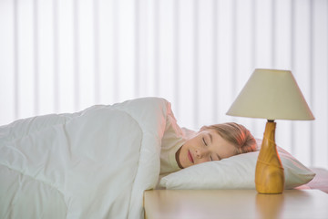 The cute girl sleeping on the bed with white linens