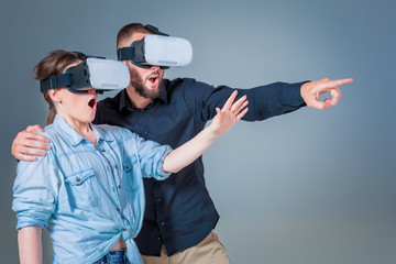 Excited young man and woman having fun with a VR glasses