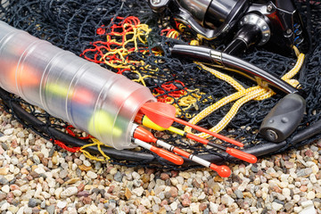 Fishing floats in the storage box with fishing rod reel and fish tank on the stony ground