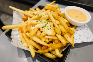 French fries with powder cheese and mayonnaise sauce serve on black plate for food background.
